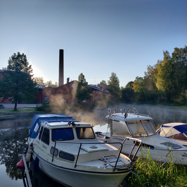 Aurinkoinen syysaamu Loimijoella. Usva nousee joen pinnasta ja nousevan auringon valo valaisee veneitä joella.