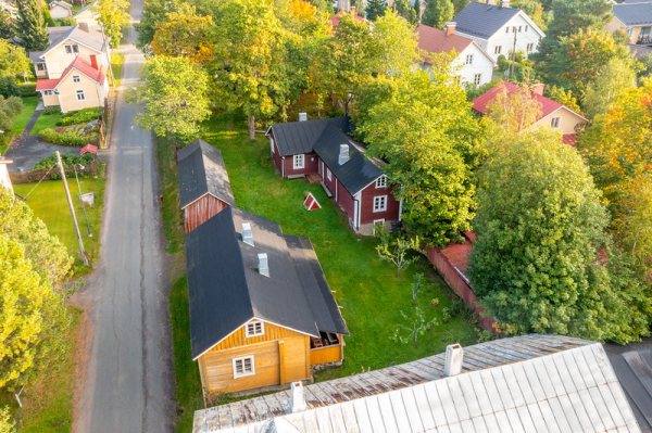 Vanhoja puutaloja vehreän kesäisessä maisemassa.