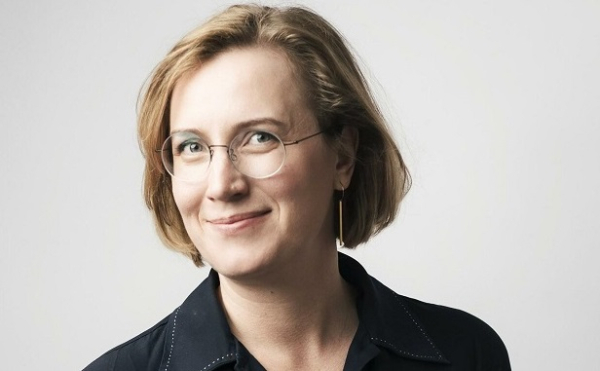 Hymyilevä silmälasipäinen nainen katsomassa kameraan.