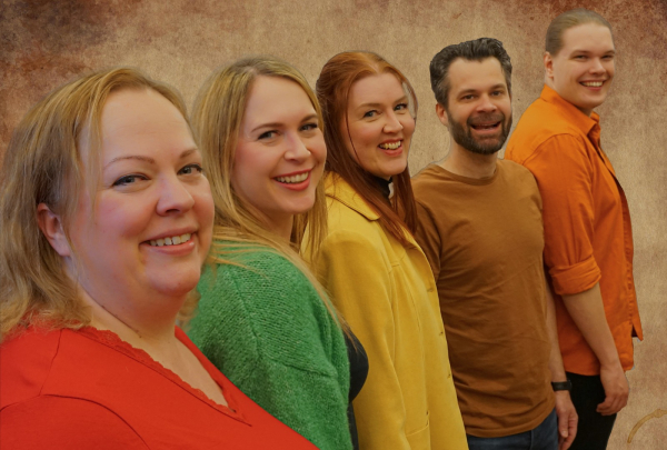 Kuvassa viisi hymyilevää näyttelijää rivissä.