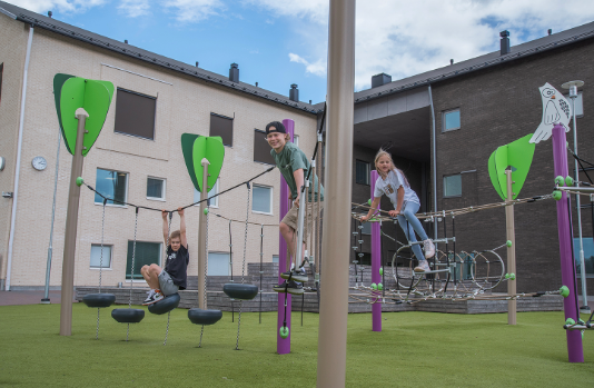 Lapsia kiipeilemässä koulun pihan kiipeilytelineissä.