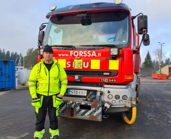 Mies seisomassa vakavana punaisen kuorma-auton edessä.